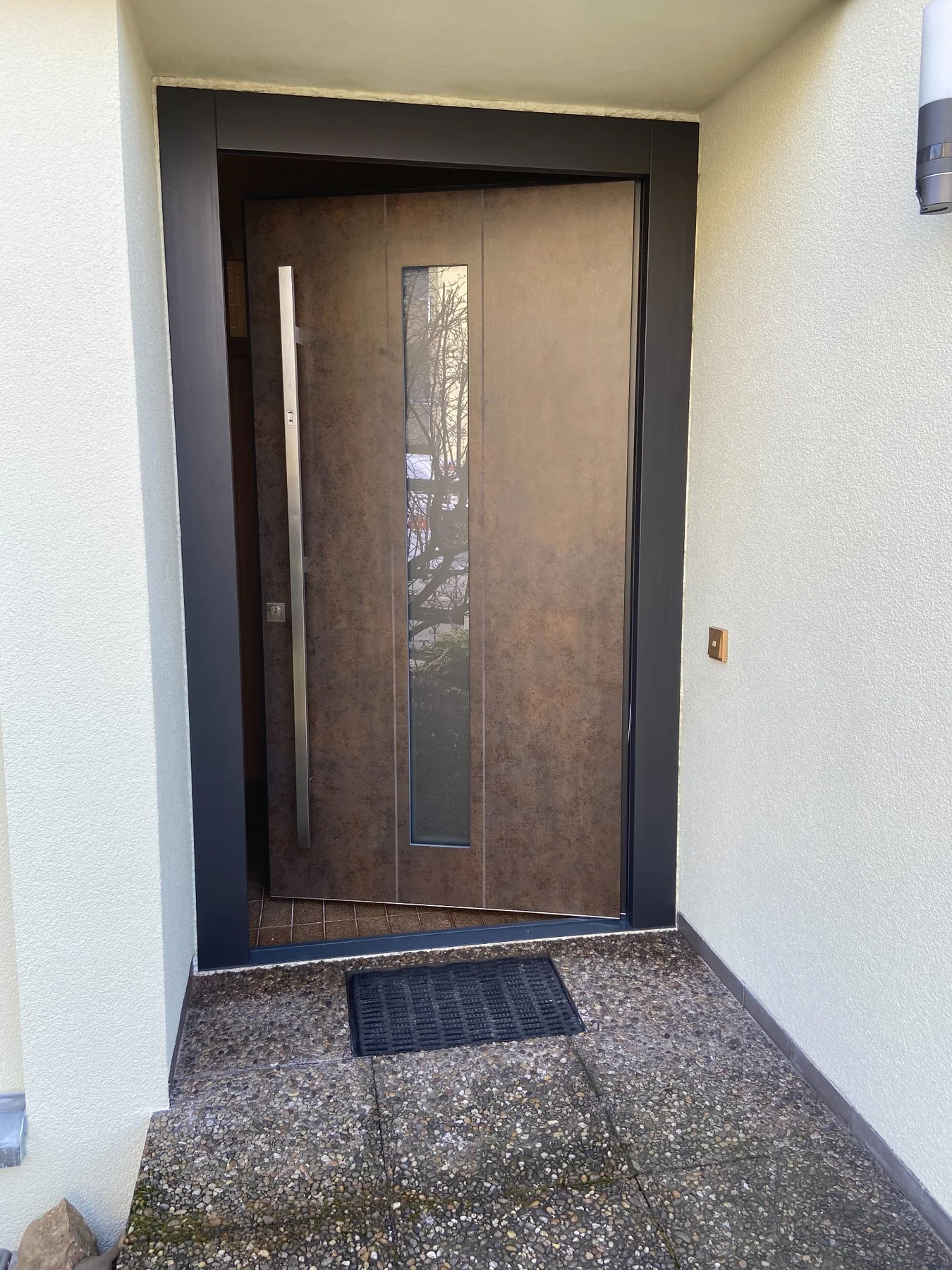 Haustür in Betonoptik mit schmalem vertikalem Glasausschnitt